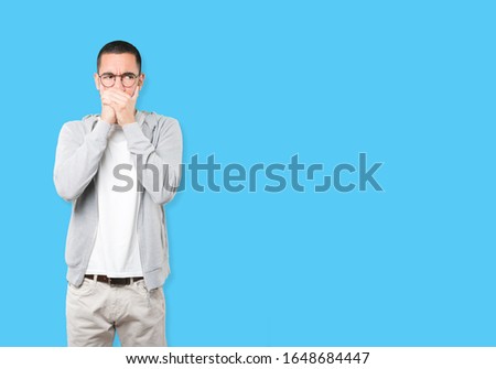 Young man covering his mouth with his hands