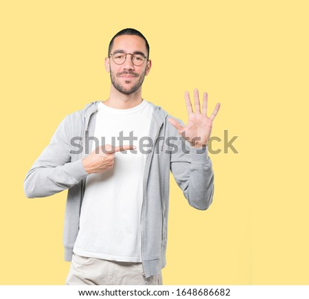 Young man making a number five gesture