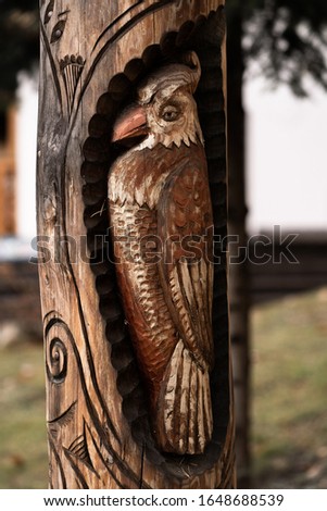 beautiful figures carved into a tree nature landscape background. A wooden bird figure carved in a tree trunk.