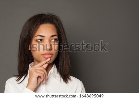 Clever student black woman brunette thinking on gray background. Brainstorming concept