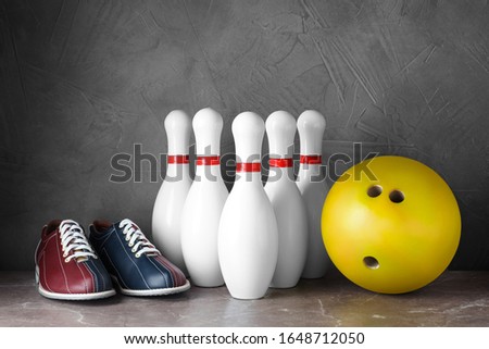 Bowling shoes, pins and ball on grey marble table
