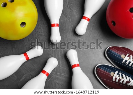 Bowling shoes, pins and balls on grey stone table, flat lay