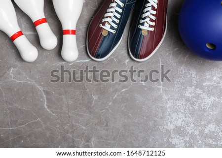 Bowling shoes, pins and ball on grey marble table, flat lay. Space for text
