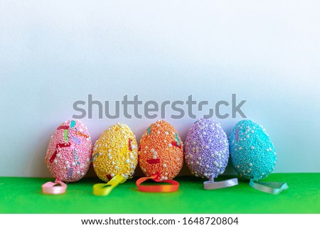 Colorful easter eggs standing on the grassy green surface and white background. Easter holidays concept. Copyspace, place for text and wording. April vibes