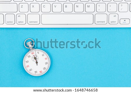 Gray keyboard with a stopwatch with blue background with copy space