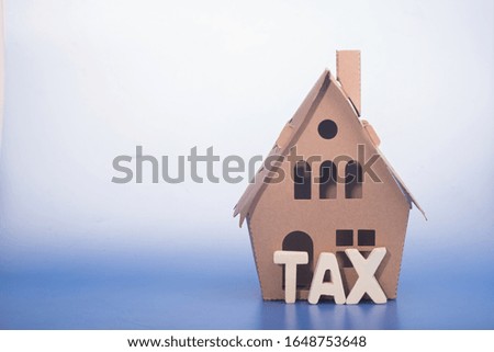 Miniature house from card box with the 'tax' word, property tax concept