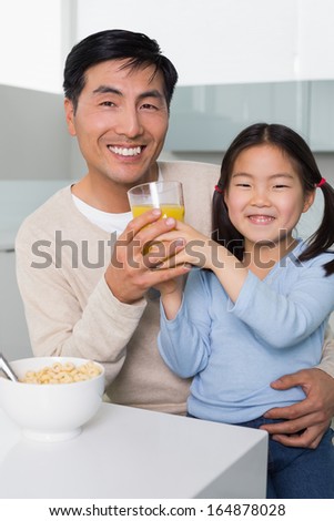 Portrait of a happy father with young daughter having breakfast in the kitchen at home