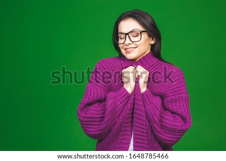Young cheerful beautiful girl wearing winter cozy sweater isolated over green background. 