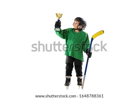 Champion. Little hockey player with the stick on ice court and white studio background. Sportsboy wearing equipment and helmet training. Concept of sport, healthy lifestyle, motion, movement, action.