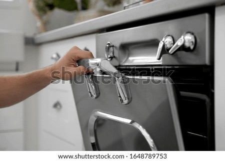 Man using modern oven in kitchen, closeup