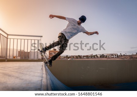 young skateboarder doing a backside 5-0 on ramp. Behind him, the sun is falling