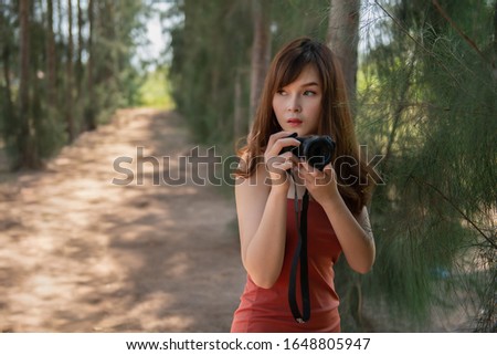 Portrait of a photographer  with the camera outdoor. Asian woman  holding digital camera in her hand free from copy space.