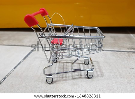 Little shopping cart on White Tiles and Orange Background