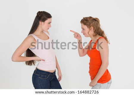 Angry young female friends having an argument over white background