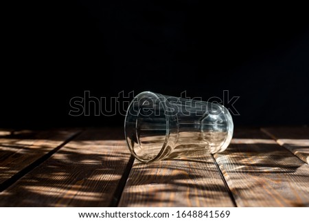 empty transparent glass on a dark background. horizontal brown wooden table. bright sun