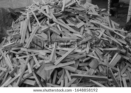 Stack of cut firewood of different size on a black and white background close up.