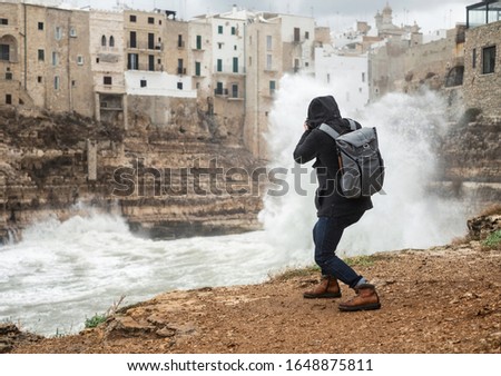 Photographer taking picture of a stormy sea in Polignano a Mare, Italy