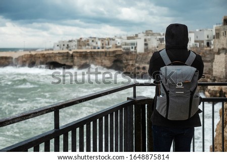 Tourist enjoying view  of a stormy sea in Polignano a Mare, Italy