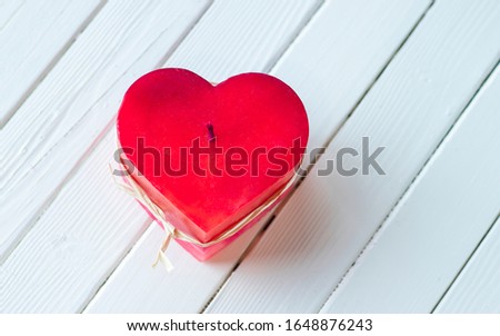 Pink heart candle with white wood background.