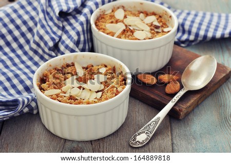 Apple crumble in ceramic molds with fresh apples on wooden background