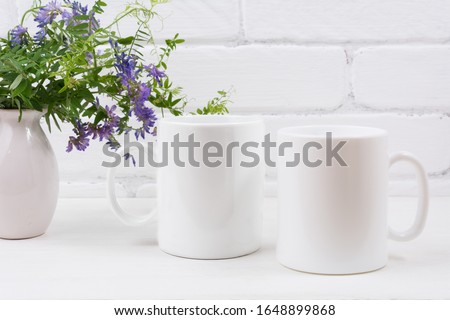 Two white coffee  mug mockup with purple mouse peas flowers.  Empty mug mock up for design promotion.    Royalty-Free Stock Photo #1648899868