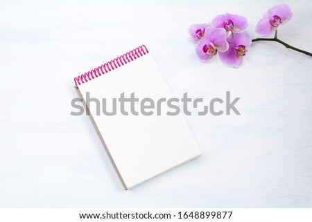 Notepad mockup with pink orchid on the white table