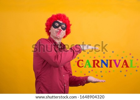 man with wig and hat blowing a noisemaker, carnival party concept