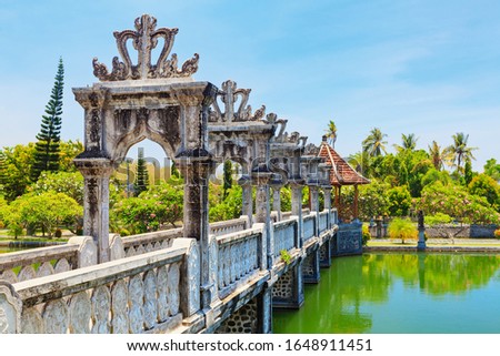 View of ancient bridge in Taman Ujung near Alampura in Karangasem on Bali Island. Water Palace of Balinese royal family with water pools, tropical landscape park. Indonesian traditional arts, culture.