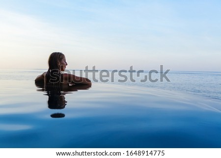 Happy girl enjoy on summer beach holiday. Young woman relaxing at edge of infinity swimming pool with sea view from hill top. Family cruise lifestyle, summer travel with kids on tropical islands.