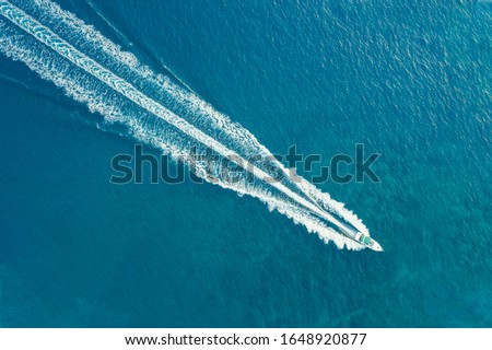 The boat is moving at high speed on the sea. A long Wake follows the boat. Blurred movement. Shooting from a drone. Royalty-Free Stock Photo #1648920877