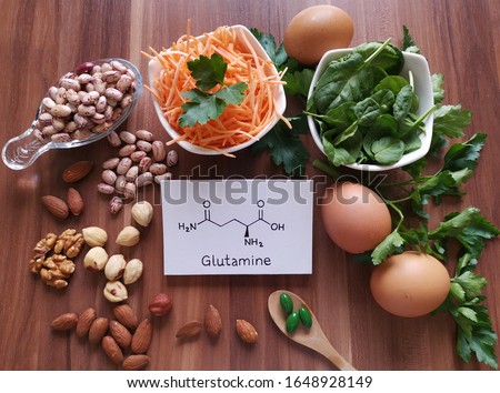 Food rich in glutamine with structural chemical formula of glutamine molecule. Food for training and exercise: spinach, egg, parsley, carrot, bean, almond, walnut, pills. Bodybuilding, sport nutrition Royalty-Free Stock Photo #1648928149