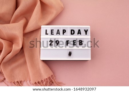 White block calendar present date 29 and month February and scarf on pink background. Leap day