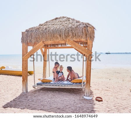 Family relaxing at sea.  Little blonde daughter with dad and mom on deck chair by the sea.