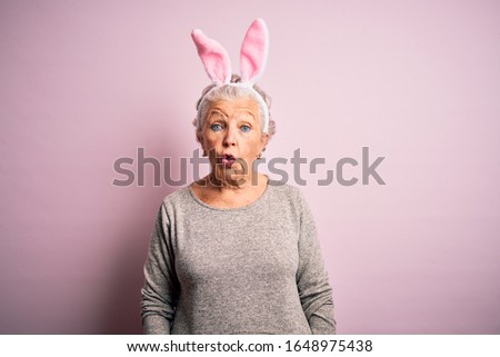 Senior beautiful woman wearing bunny ears standing over isolated pink background afraid and shocked with surprise expression, fear and excited face.