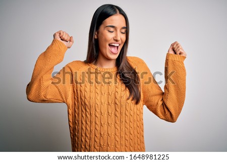 Young beautiful brunette woman wearing casual sweater over isolated white background Dancing happy and cheerful, smiling moving casual and confident listening to music