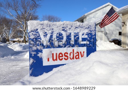 Vote sign "Vote Tuesday"  covered in snow for a spring primary
