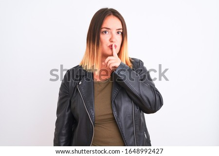 Young beautiful woman wearing t-shirt and jacket standing over isolated white background asking to be quiet with finger on lips. Silence and secret concept.