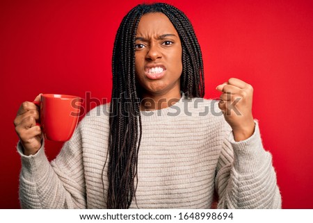 Young african american girl drinking a coffee cup over red isolated background annoyed and frustrated shouting with anger, crazy and yelling with raised hand, anger concept