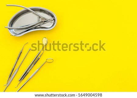 Dentak care concept. Stomatological tools in tray on yellow background top-down space for text