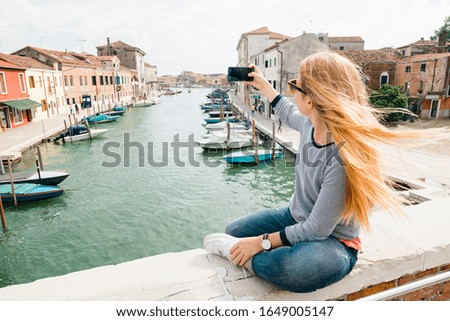 Young woman taking a phone on the bridge in Murano in Venice, Italy