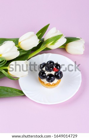 Tulip bouquet and mignon cake closeup. Springtime. Womens and Mothers Day concept. Spring greeting card. Copy space. Selective focus.Vertical.