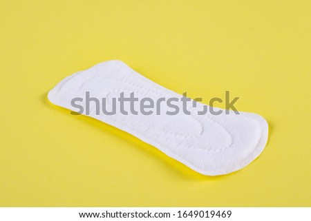 One sanitary pad on a yellow background.