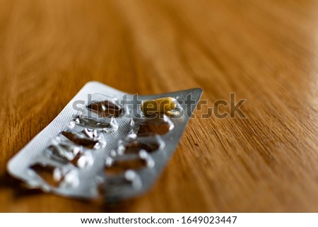 Yellow, oval-shaped tablets in capsules, absorbable shell with powder inside, silver blister packaging on a wooden table