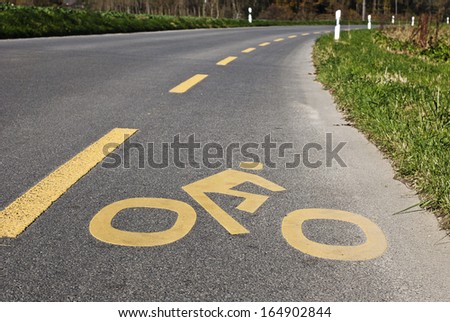 A yellow cycle sign on a cycle lane on a country road