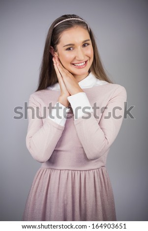Cheerful pretty model with pink dress on posing on grey background