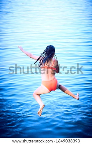The girl in a swimsuit is jumping into the water