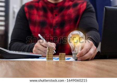 
a desk with a light bulb and money a man focused on his work