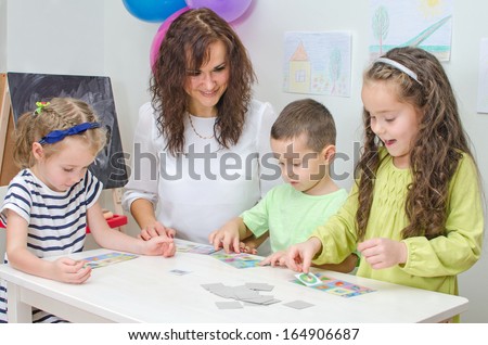 Teacher plays with children in kindergarten. Royalty-Free Stock Photo #164906687