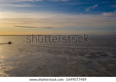 Lonely lighthouse on winter evening on frozen ocean
