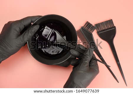 Girl in black gloves mixes hair dye in a bowl Royalty-Free Stock Photo #1649077639